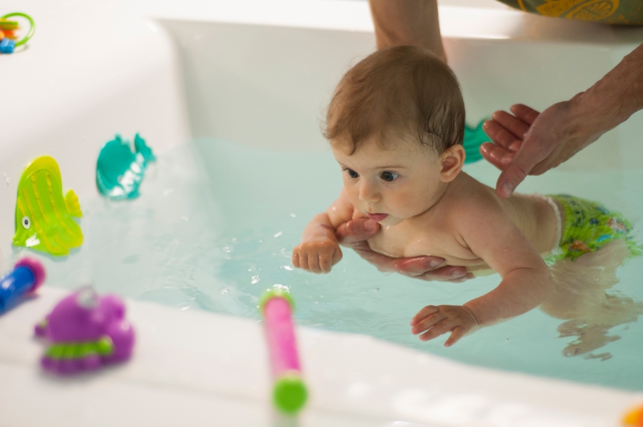Ребенок плавает в ванне с игрушками