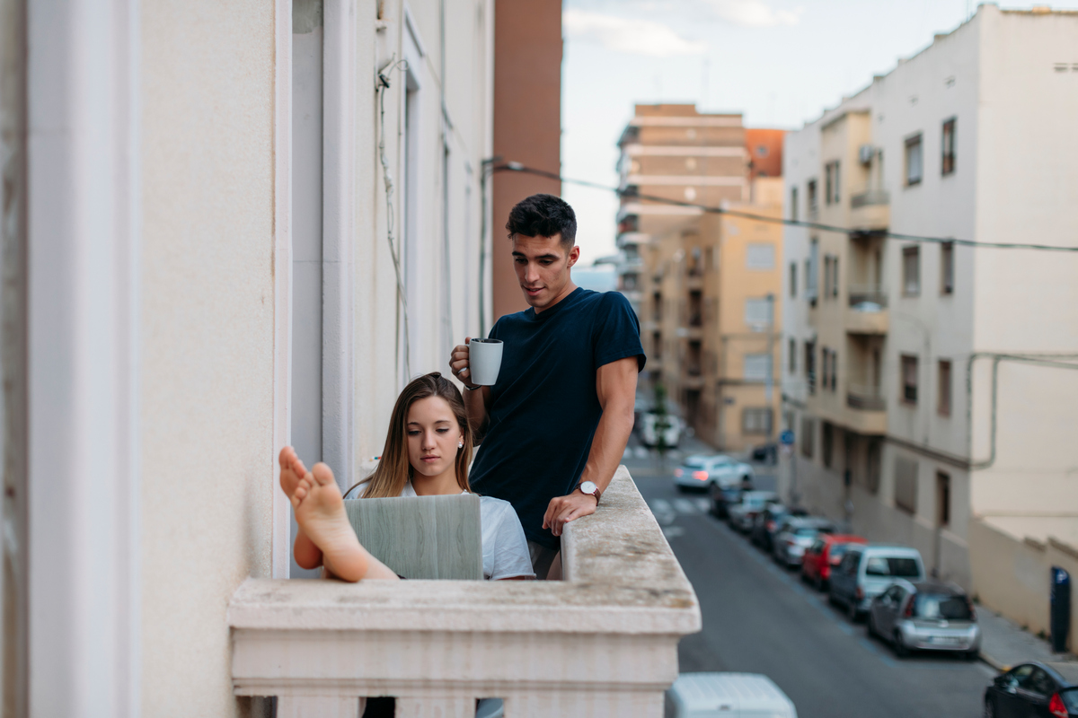 Молодая пара на балконе с компьютером