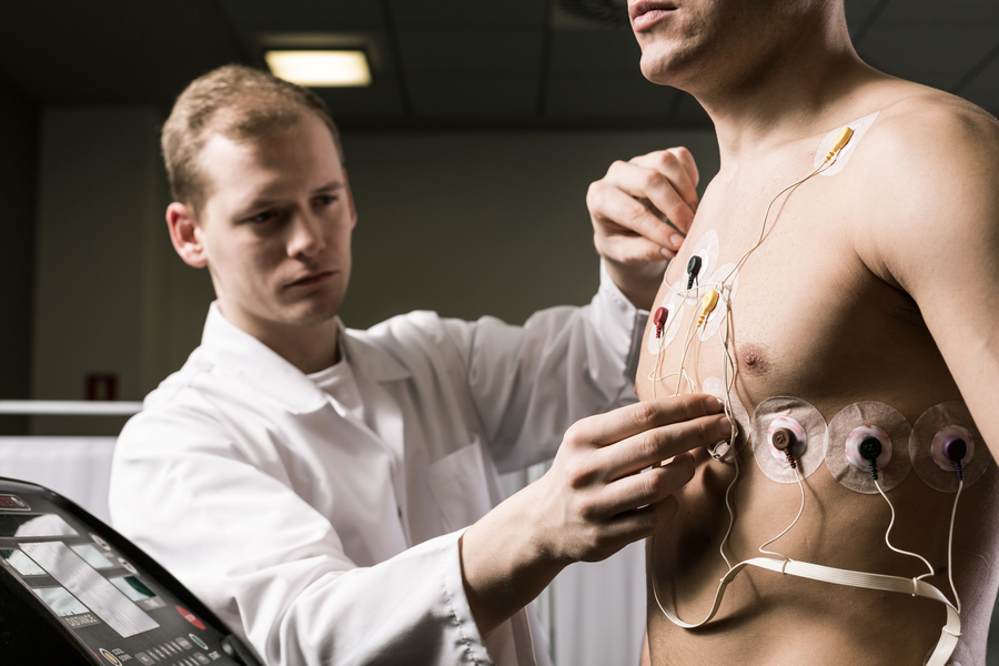 Доктор устанавливает мужчине электроды кардиограммы