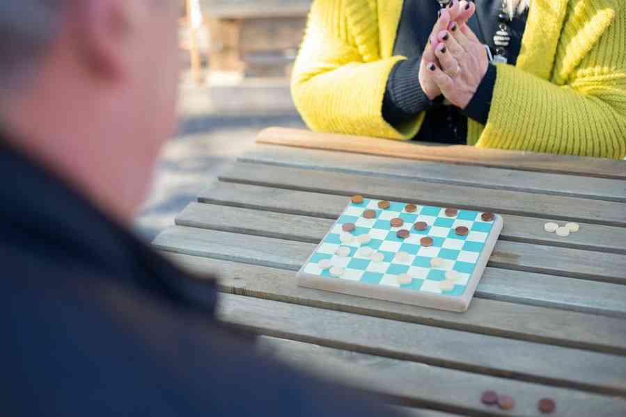 Женщина и мужчина играют за столом в шашки на улице