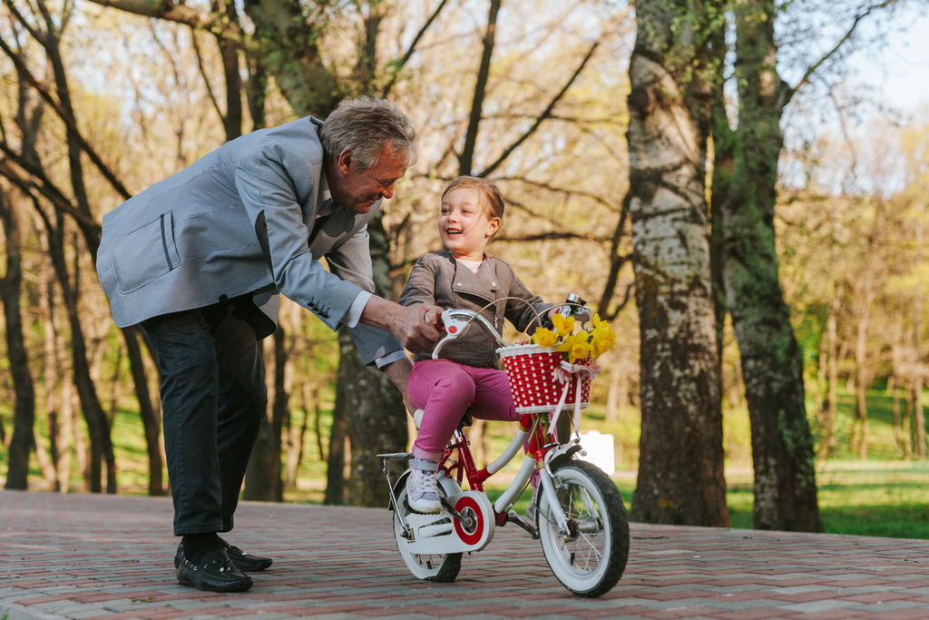 Дедушка учит внучку кататься на велосипеде