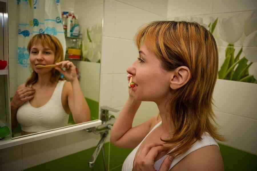 Девушка чистит зубы перед зеркалом