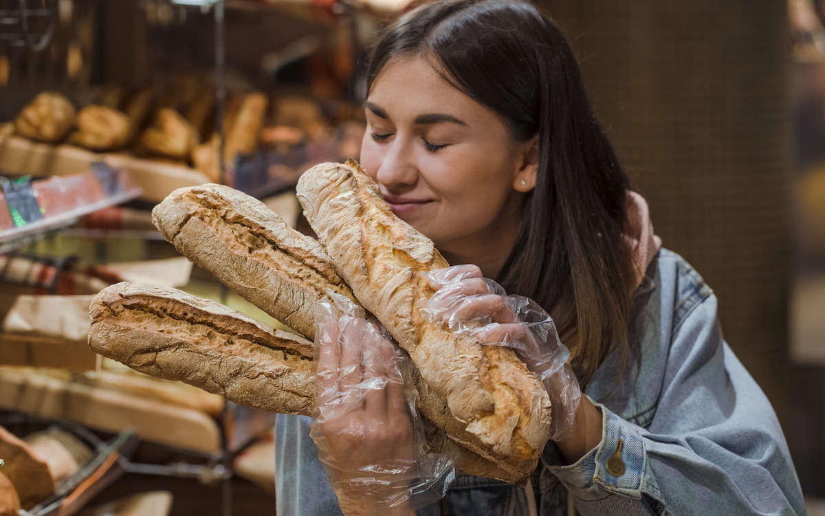 Девушка в супермаркете нюхает хлеб