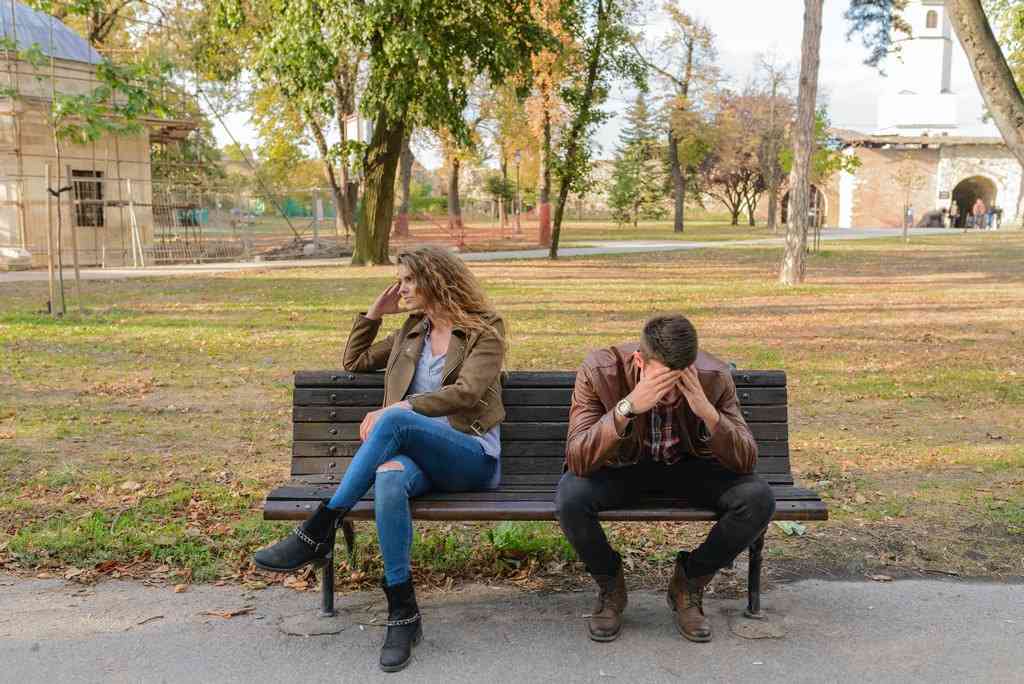 Девушка и парень сидят на скамейке в стрессе и мучаются головной болью