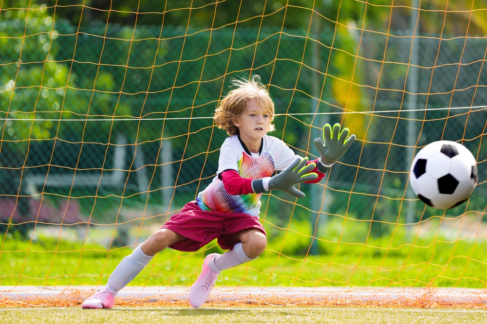 Мальчик в футбольной секции стоит на воротах