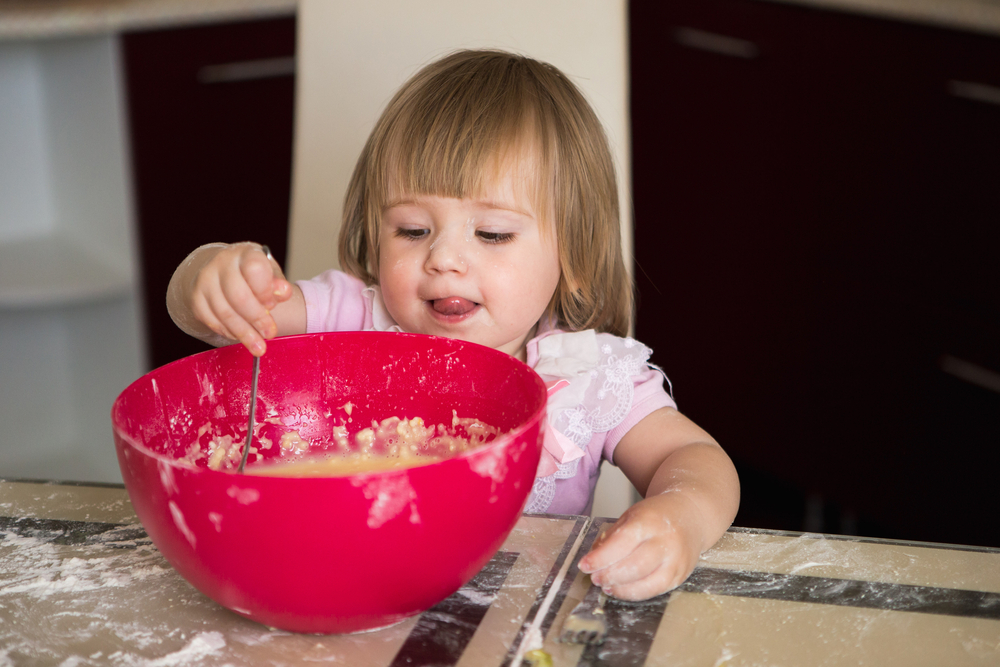 Трехлетняя девочка помогает родителям готовить еду