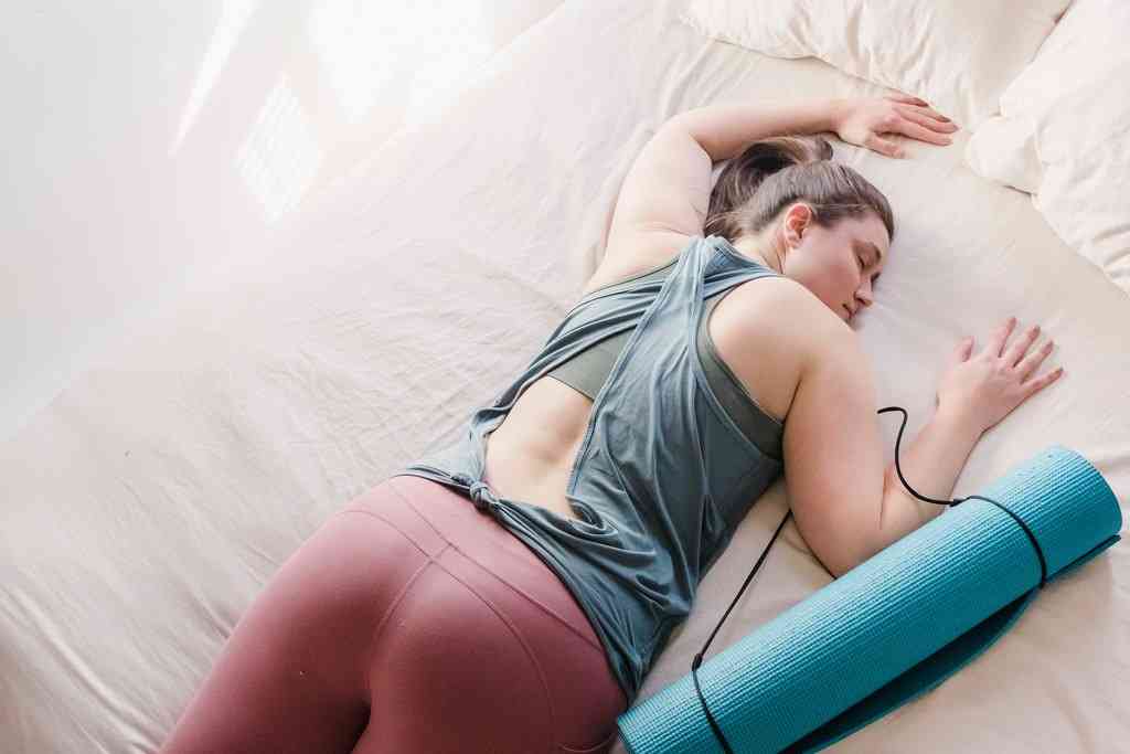 Девушка спит на животе со спортивным ковриком