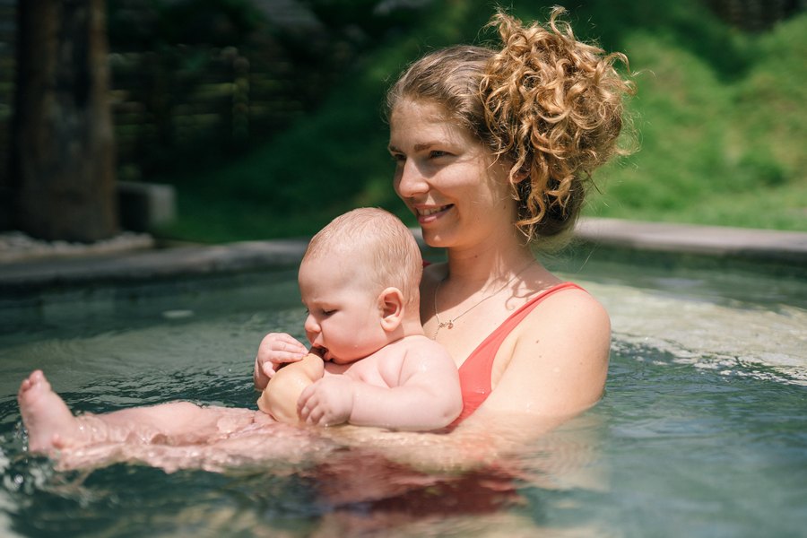 Мама учит плаванию грудничка в бассейне на природе