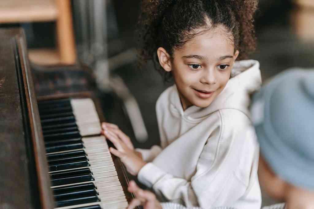 Девочка играет на пианино и улыбается