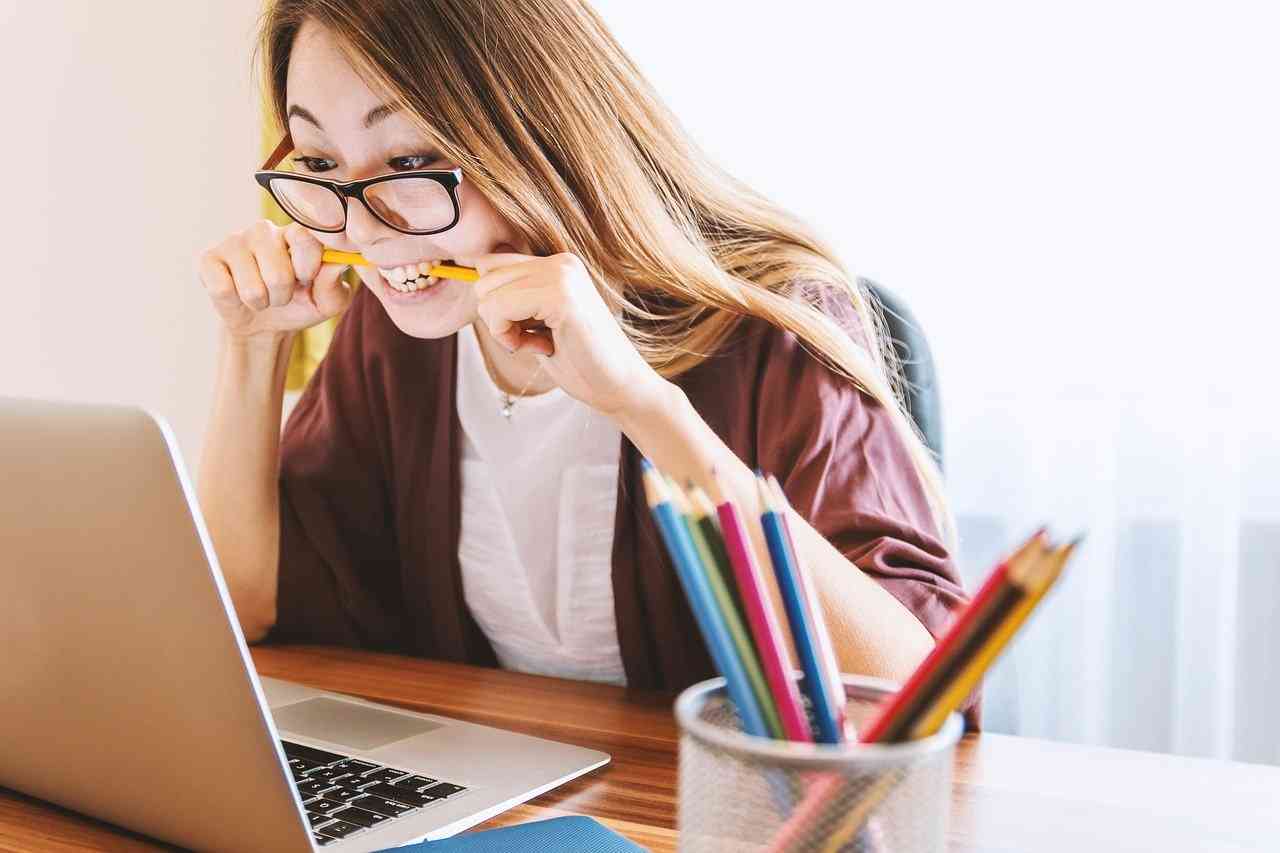 Девушка в стрессе сидит перед компьютером и грызет карандаш
