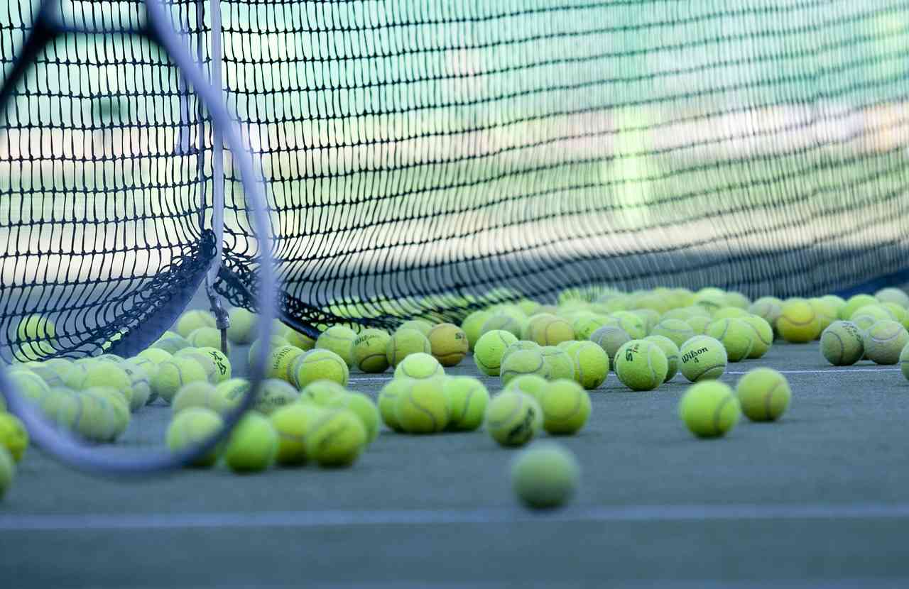 Много теннисных мячиков на корте возле сетки