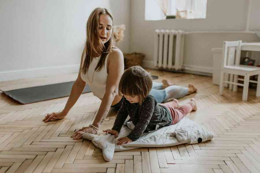 Мама с дочкой занимаются йогой на коврике дома