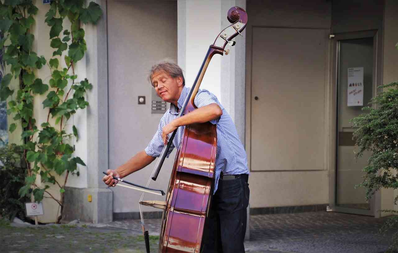 Мужчина в возрасте играет на виолончели во дворе