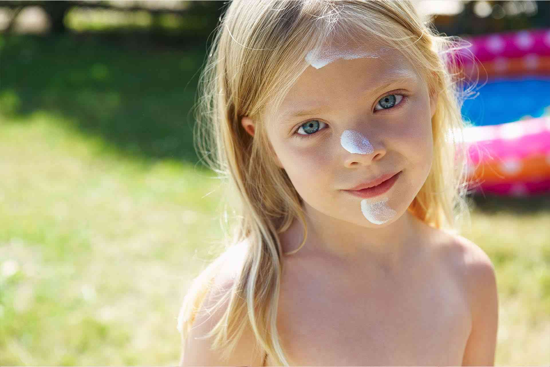 Ребенок наносит на лицо солнцезащитный крем