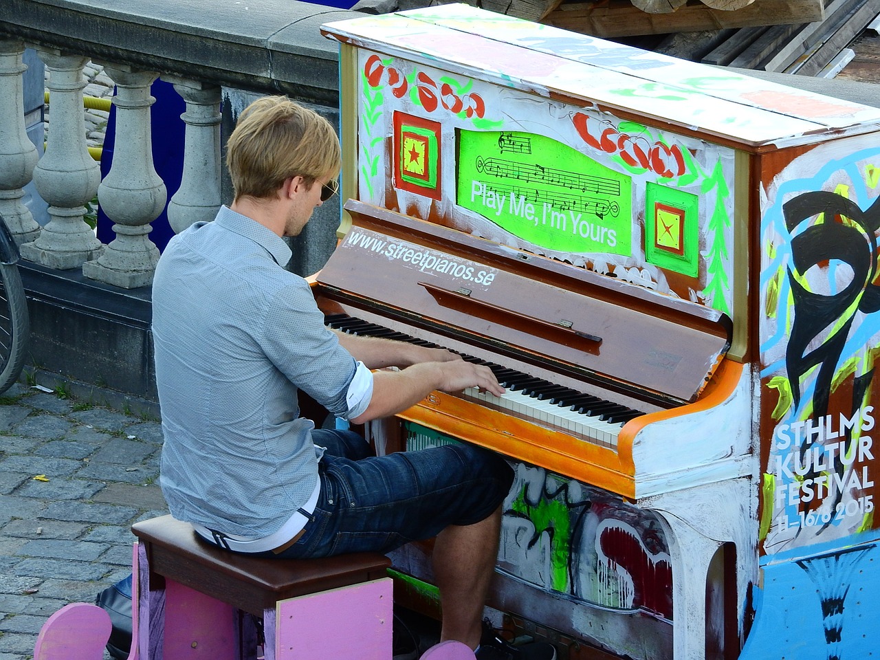 Парень играет на уличном раскрашенном пианино