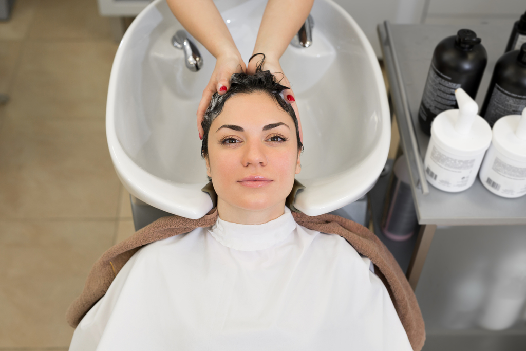 Женщина в процессе мытья волос в парикмахерской